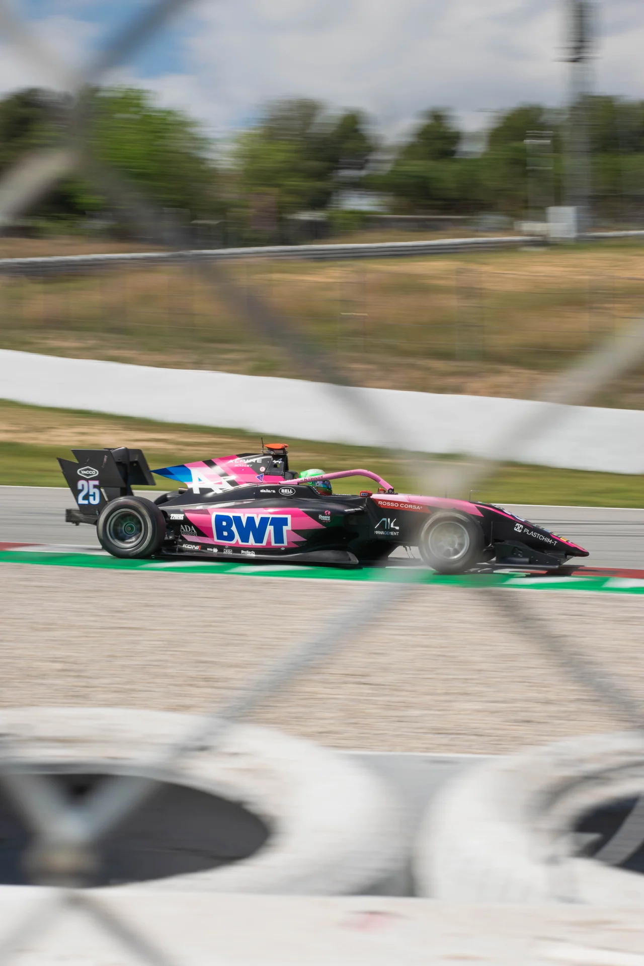 A pink Formula single-seater at speed, photographed trackside